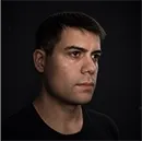 Portrait of Martín Viera with his face turned slightly to the right, a serious expression, wearing a black T-shirt, against a dark background with soft lighting.