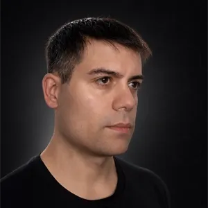 Portrait of Martín Viera with his face turned slightly to the right, serious expression, black T-shirt, dark background with soft lighting.