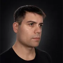 Portrait of Martín Viera with his face turned slightly to the right, serious expression, black T-shirt, dark background with soft lighting.